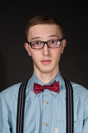 man in a red  bow tie plaid shirt looking over glasses on a black backgroundの写真素材
