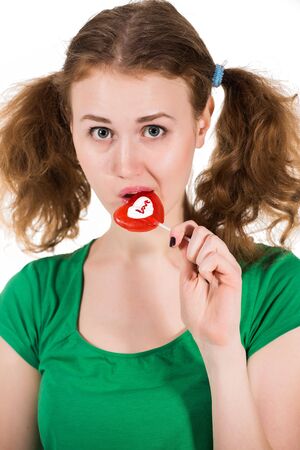 closeup shot of girl with red heart lollipop isolated on whiteの写真素材
