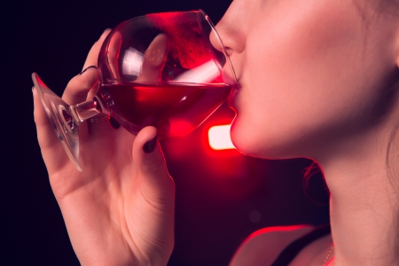 Beautiful girl drinking red wine on black backgroundの写真素材