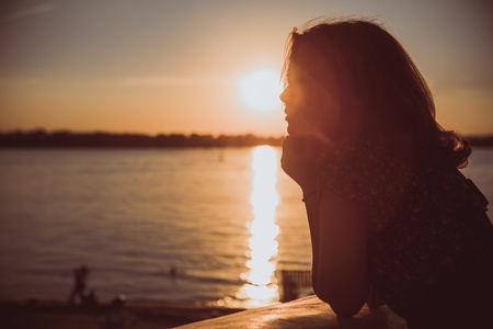 Beautiful young brunette girl sitting outdoors near the riverの写真素材