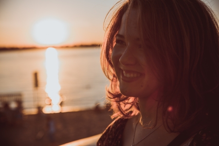 Beautiful young brunette girl sitting outdoors near the riverの写真素材