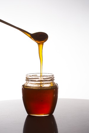 glass of fresh honey on white backgroundの写真素材