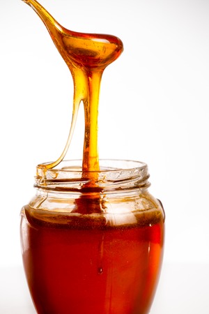 glass of fresh honey on white backgroundの写真素材