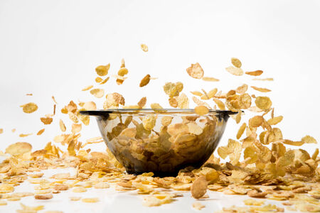 Cornflakes falling into a pile, over white 