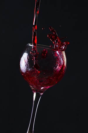 Red Wine Pouring into glass black isolatedの写真素材