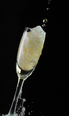 Glass of champagne with splash, isolated on black backgroundの写真素材