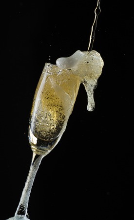 Glass of champagne with splash, isolated on black backgroundの写真素材