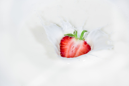 Strawberry falling into splashing milk. Isolated on white.の写真素材