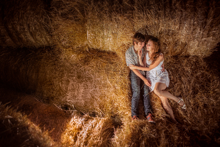 Young boy and gyrl lying in hay.  Outdoor  summer portrait of beautiful couple.の写真素材