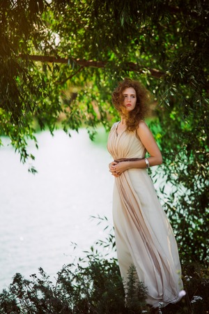 female model in long beige  dress posing dynamic in the beach. waving fabric. fluttering long skirtの写真素材