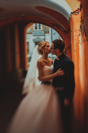 Closeup portrait of bride and groom kissing in ancient tunnel made of bricksの写真素材