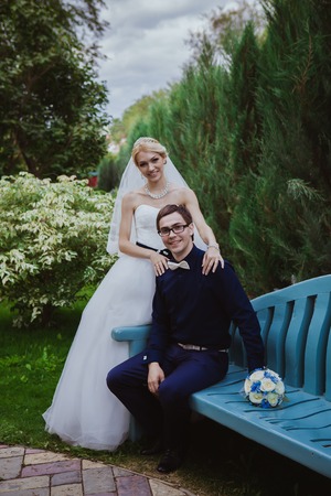 Wedding shot of bride and groom sit on bench in parkの写真素材