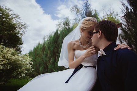 Wedding shot of bride and groom sit on bench in parkの写真素材