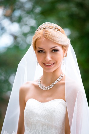 portrait of beautiful young woman in white dress walking in parkの写真素材