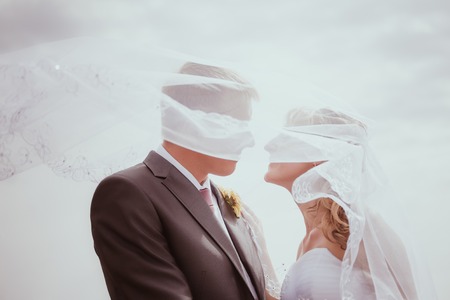 Kissing wedding couple in high grassの写真素材