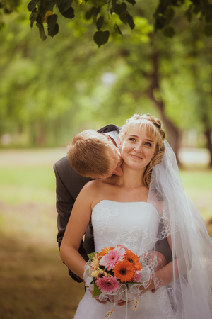 Bride and groom in a park kissing.couple newlyweds bride and groom at a wedding in nature green forest are kissing photo portrait.Wedding Couple Loveの写真素材