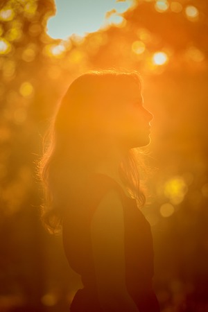 Young pretty woman  in the autumn park profile  view backlit by sunset headshotの写真素材