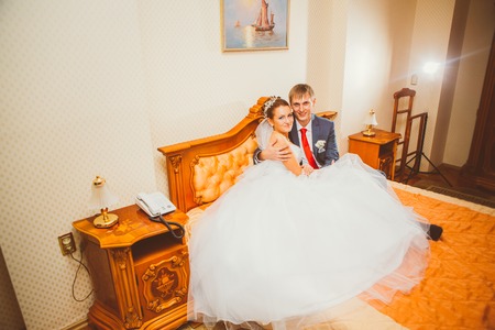 Wedding shot of bride and groom  lying in a stylish bedの写真素材