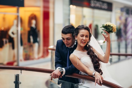 Happy bride and groom embracing  in the spacious hall of the shopping complexの写真素材