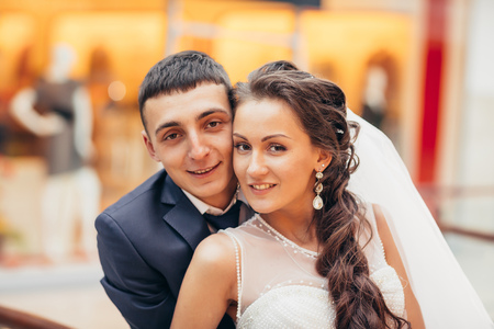 Happy bride and groom embracing  in the spacious hall of the shopping complexの写真素材