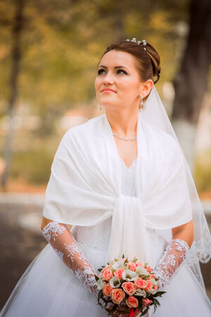 Beautiful bride in wedding dress and  bridal bouquet, happy newlywed woman with wedding flowers, woman with wedding makeup and hairstyle. gorgeous young bride outdoors. Bride waiting for groom. brideの写真素材