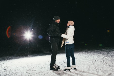 Couple ice skating outdoors on a pond on nightの写真素材