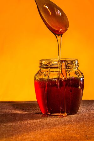 Honey jar with spoon and flowing honey, canvas backgroundの写真素材
