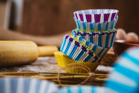 Colorful cupcake wrappers  with baking pan on kitchen background