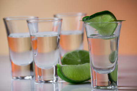Tequila shot with a slice of lime on the glass on  orange backgroundの写真素材