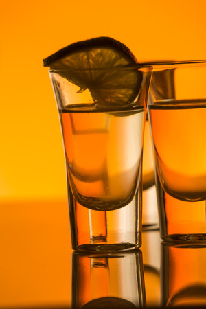 Tequila shot with a slice of lime on the glass on  orange backgroundの写真素材