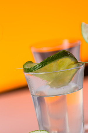 Tequila shot with a slice of lime on the glass on  orange background. Selective Focusの写真素材