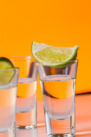 Tequila shot with a slice of lime on the glass on  orange background. Selective Focusの写真素材