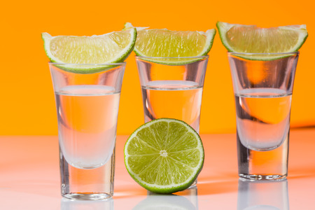 Tequila shot with a slice of lime on the glass on  orange background. Selective Focusの写真素材