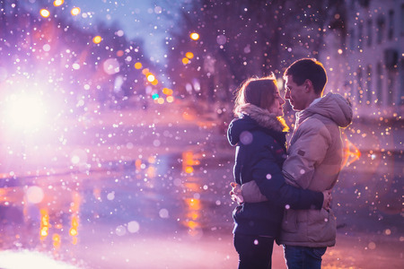 In love couple in the snow at night city street. Filtered with grain and light flashingの写真素材