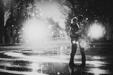 In love couple kissing in the snow at night city street, black and whiteの写真素材