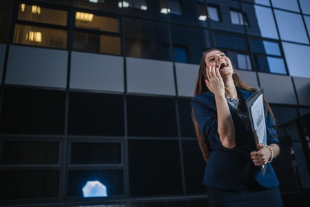 Successful beautiful young business woman standing against a background of  buildings and holding...