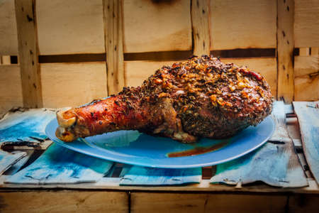 great fresh baked turkey  leg and sliced piece sprinkled with spices lying on a blue plate to black wooden backgroundの写真素材