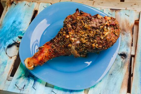 great fresh baked turkey  leg and sliced piece sprinkled with spices lying on a blue plate to black wooden backgroundの写真素材