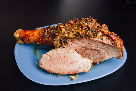 great fresh baked turkey  leg and sliced piece sprinkled with spices lying on a blue plate to black wooden backgroundの写真素材
