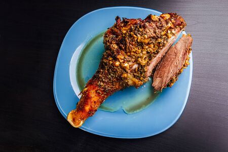 great fresh baked turkey  leg and sliced piece sprinkled with spices lying on a blue plate to black wooden backgroundの写真素材