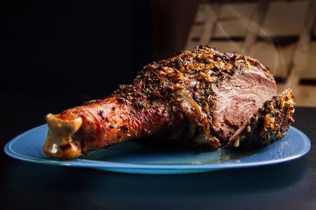 great fresh  baked turkey leg sprinkled with spices lying on a blue plate to  black wooden backgroundの写真素材