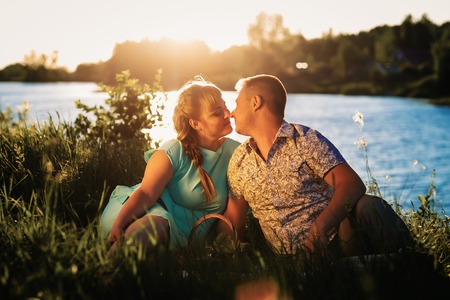 Romantic  couple sit and  kissing  on background summer lakeの写真素材