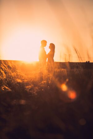Romantic couple standing  and kissing on background summer meadow sunsetの写真素材