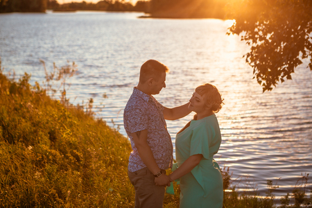 Romantic couple standing  and kissing on background summer lake sunsetの写真素材