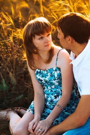 Romantic couple standing  and kissing on background summer meadow sunsetの写真素材