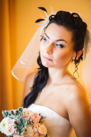 beautiful young happy bride standing near the windowの写真素材