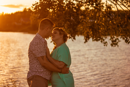 Romantic couple standing  and kissing on background summer lake sunsetの写真素材