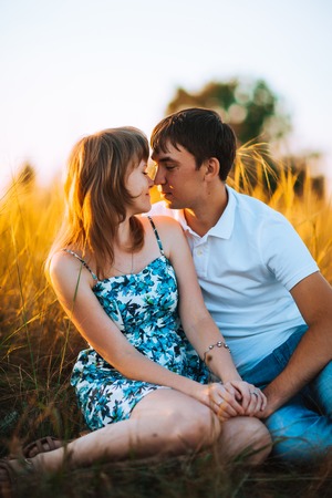 Romantic couple standing  and kissing on background summer meadow sunsetの写真素材
