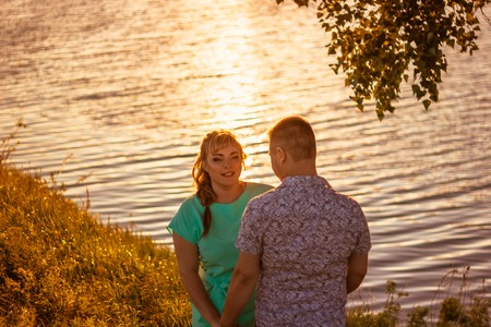 Romantic couple standing  and kissing on background summer lake sunsetの写真素材