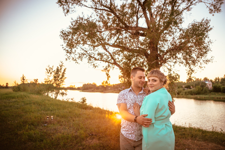 Romantic couple standing  and kissing on background summer meadow sunsetの写真素材